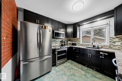 Kitchen featuring dark wood-finish cabinetry, stainless steel appliances, a mosaic tile backsplash, and a double basin sink - 