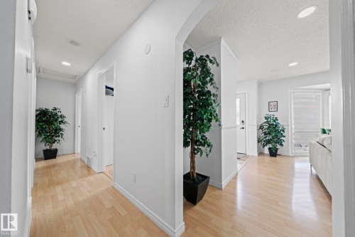 Hallway featuring light wood-finish flooring, recessed lighting, white walls, and an arched entryway - 5418 17A Avenue, Edmonton, AB 