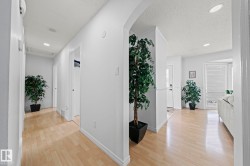 Hallway featuring light wood-finish flooring, recessed lighting, white walls, and an arched entryway - 