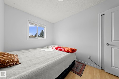 Room featuring wood-finish flooring and a white paneled door with brushed nickel hardware - 5418 17A Avenue, Edmonton, AB 