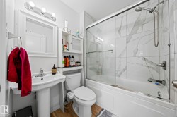 Bathroom featuring a white pedestal sink with chrome faucet, a wall-mounted mirror, a three-bulb vanity light, and a toilet - 