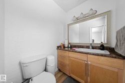 Bathroom vanity featuring wood cabinetry with multiple drawers and doors, a dark countertop, and an integrated white sink - 