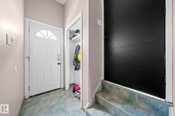 Entryway featuring a white paneled door with a sunburst transom window, a closet with shelving and hanging rod, light gray walls, and green tile flooring - 