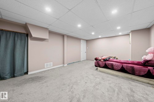 Spacious room featuring light gray carpet flooring, neutral painted walls, and a white acoustical tile ceiling with recessed lighting - 5418 17A Avenue, Edmonton, AB 