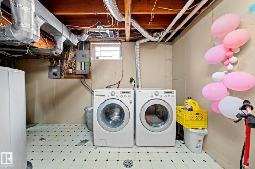 Utility area featuring a front-load washer and dryer, exposed ceiling joists, and a partial block window - 5418 17A Avenue, Edmonton, AB 