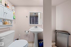 Pedestal sink with chrome fixtures, wall-mounted mirror, and tile flooring - 