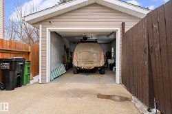 Detached garage with light-colored siding, a white overhead door, and a concrete approach - 