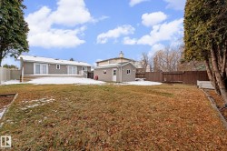 Spacious backyard with a detached shed, a full privacy fence, and a multi-level deck featuring multiple sets of double doors - 