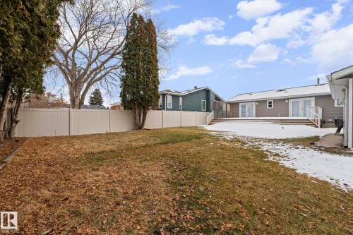 Expansive backyard featuring a partial lawn, mature trees, and a light-colored privacy fence - 5418 17A Avenue, Edmonton, AB 