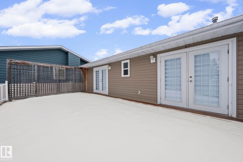 Expansive exterior deck featuring a privacy trellis, white railing, and dual glass-paneled French doors - 5418 17A Avenue, Edmonton, AB 