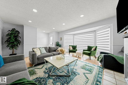 Spacious living area featuring a bay window, recessed lighting, crown molding, chair rail molding, and wood-finish flooring - 5418 17A Avenue, Edmonton, AB 
