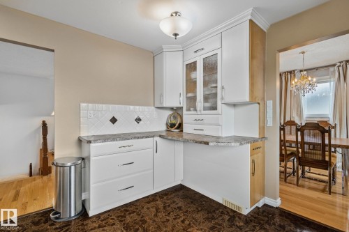 Kitchenette featuring white cabinetry, textured tile backsplash with diamond accents, and a stone-finish countertop - 10715 33 Avenue, Edmonton, AB 
