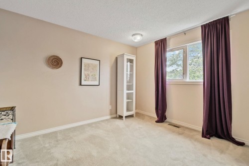 Spacious room featuring neutral-toned walls, light-colored carpeting, and a large window - 10715 33 Avenue, Edmonton, AB 
