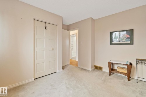 Carpeted room featuring a bifold closet, painted walls, and white trim - 10715 33 Avenue, Edmonton, AB 