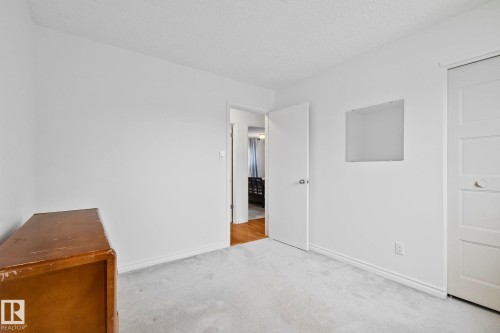 Carpeted room featuring white walls, white trim, and a white interior door - 10715 33 Avenue, Edmonton, AB 