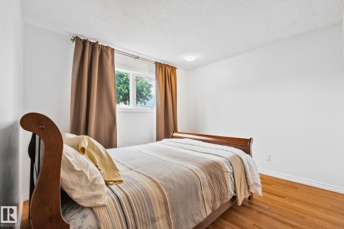 Bright room featuring a window with brown drapery, white walls, and wood-finish flooring - 10715 33 Avenue, Edmonton, AB 
