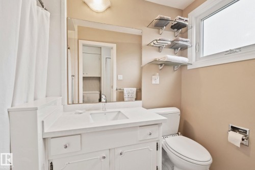 White vanity with integrated sink, chrome faucet, and mirrored backsplash - 10715 33 Avenue, Edmonton, AB 