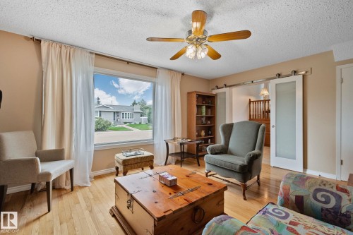 Living area featuring wood-finish flooring and a ceiling fan with light fixture - 10715 33 Avenue, Edmonton, AB 