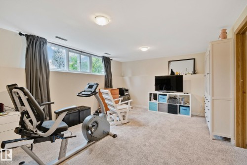 Carpeted room featuring egress window wells, recessed ceiling lighting, and built-in storage cabinetry - 10715 33 Avenue, Edmonton, AB 