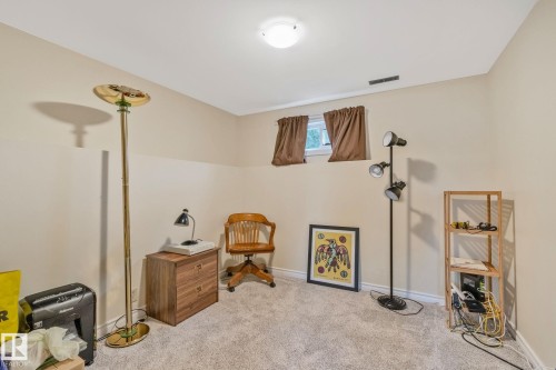 Carpeted room featuring neutral wall tones, two ground-level windows with brown window treatments, and a ceiling-mounted light fixture - 10715 33 Avenue, Edmonton, AB 