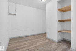 Room featuring wood-finish flooring, white walls, and built-in shelving - 