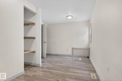 Room featuring wood-finish flooring, a neutral color palette, and a built-in shelving unit - 