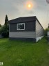 Exterior featuring dark textured siding, light-toned horizontal paneling, and a white-framed window - 543 Evergreen Street, Edmonton, AB 