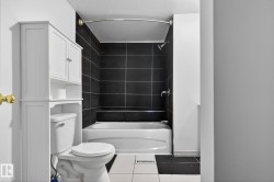 Full bathroom featuring a white bathtub with a black tiled shower surround - 