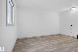Spacious room featuring wood-finish flooring, white walls, and a single pane window - 