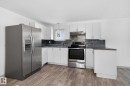 Kitchen featuring wood-finish flooring, white cabinetry, granite-look countertops, and a stone-tile backsplash - 543 Evergreen Park Northwest, Edmonton, AB  - Indoor Photo Showing Kitchen 