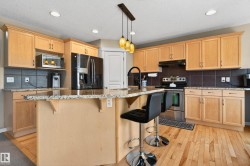 Kitchen featuring light wood cabinetry, granite-finish countertops, stainless steel appliances, and wood-finish flooring - 