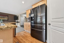 Kitchen featuring wood-finish flooring, light wood cabinetry, and a black stainless steel refrigerator - 