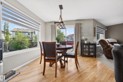 Dining area featuring wood-finish flooring, a large picture window with horizontal blinds, and access to an exterior space via sliding glass doors - 