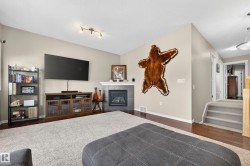 Living area featuring a fireplace with a tiled surround and white mantel, wood-finish flooring, a neutral color palette, and track lighting - 
