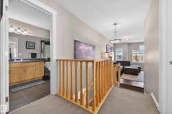Upper-level hallway featuring a light wood-toned baluster and carpeted flooring - 