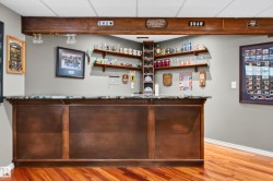 Custom built-in bar featuring wood-finish cabinetry, a stone-finish countertop, and integrated shelving - 