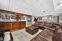 Expansive entertainment area featuring a built-in wet bar with shelving, recessed lighting, and wood-finish flooring - 