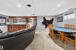 Finished lower level with recessed lighting, carpet flooring, a built-in wooden bar, and a window with blinds - 