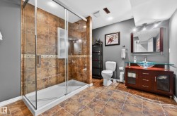 Glass-enclosed shower with brown-toned tile surround and integrated shelving - 