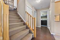 Entryway featuring wood-finish staircase railings, carpeted stairs, and a tiled floor - 