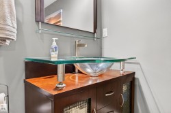 Modern vanity featuring a glass vessel sink, wood-finish countertop, and brushed nickel faucet - 