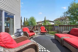 Expansive outdoor deck featuring wood railing, a durable dark area rug, and direct access to the interior via a sliding glass door - 