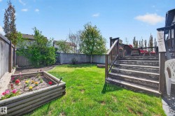 Expansive backyard featuring a multi-level wood deck, a raised garden bed, and a lush green lawn - 