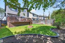 Expansive backyard featuring a manicured lawn, a raised wooden deck with lattice skirting, and a built-in fire pit - 