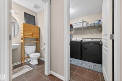 Compact half bathroom featuring a pedestal sink, round mirror, and tile flooring - 