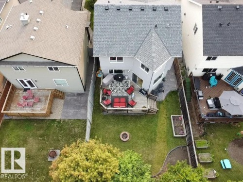Spacious backyard featuring a multi-level deck, manicured lawn, and raised garden beds - 9 Snowbird Crescent, Leduc, AB 