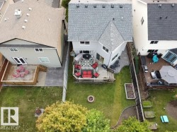 Spacious backyard featuring a multi-level deck, manicured lawn, and raised garden beds - 