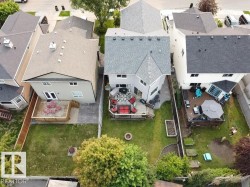 Rear exterior featuring a multi-level deck, expansive lawn, and mature trees - 