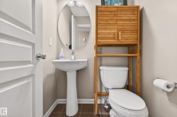 Compact bathroom featuring a white pedestal sink, oval mirror, and tile flooring - 