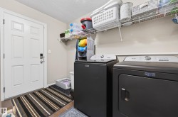 Laundry area featuring a side-by-side washer and dryer, tile flooring, and overhead wire shelving - 
